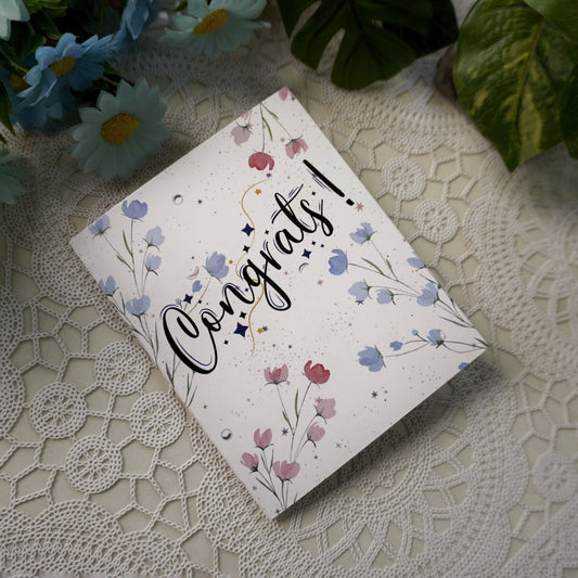 Greeting card with 'Congrats!' text on a lace surface with flowers in the background